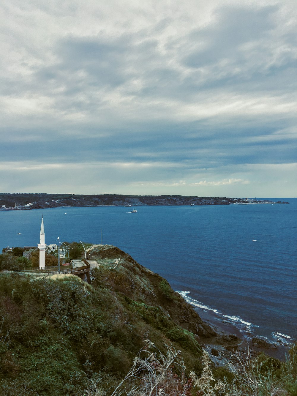 a lighthouse on a hill overlooking a body of water