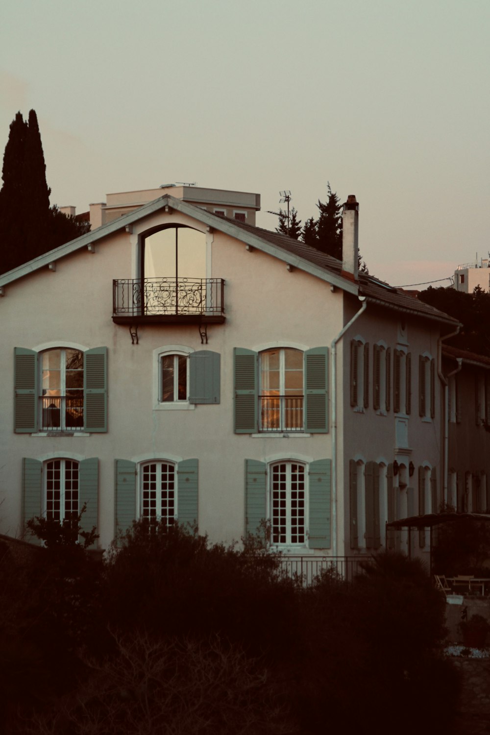 a white building with green shutters and a balcony