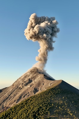 a large plume of smoke rising from the top of a mountain