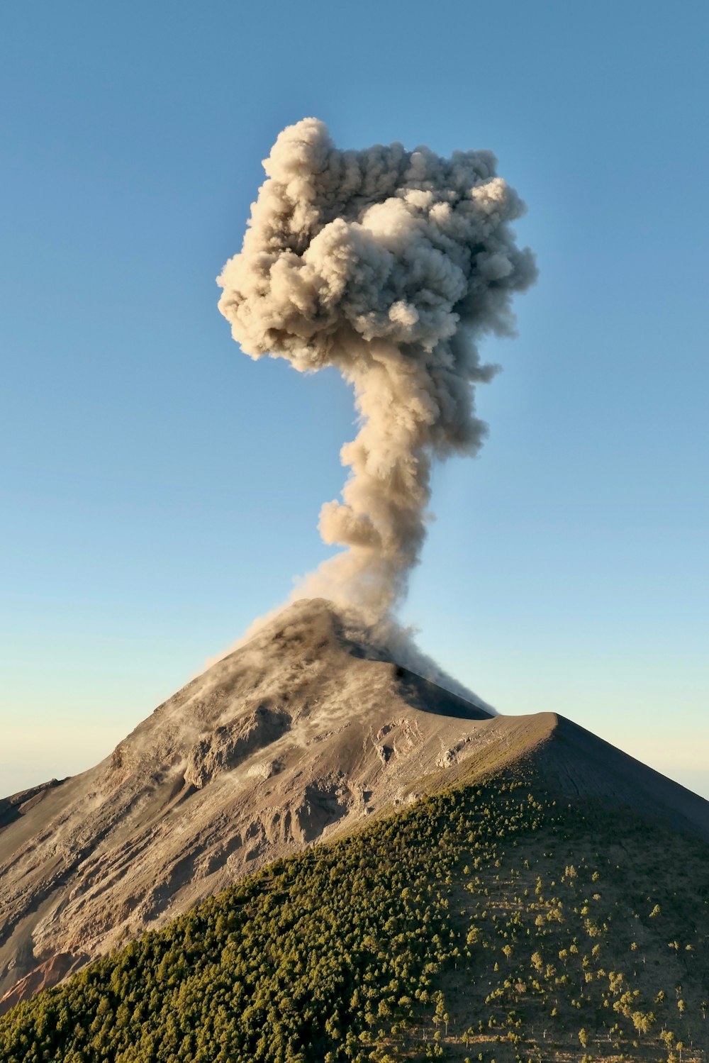 una gran columna de humo que se eleva desde la cima de una montaña