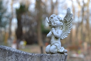 a statue of an angel sitting on top of a cement wall