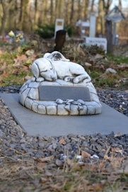 a statue of a dog laying on a stone bench