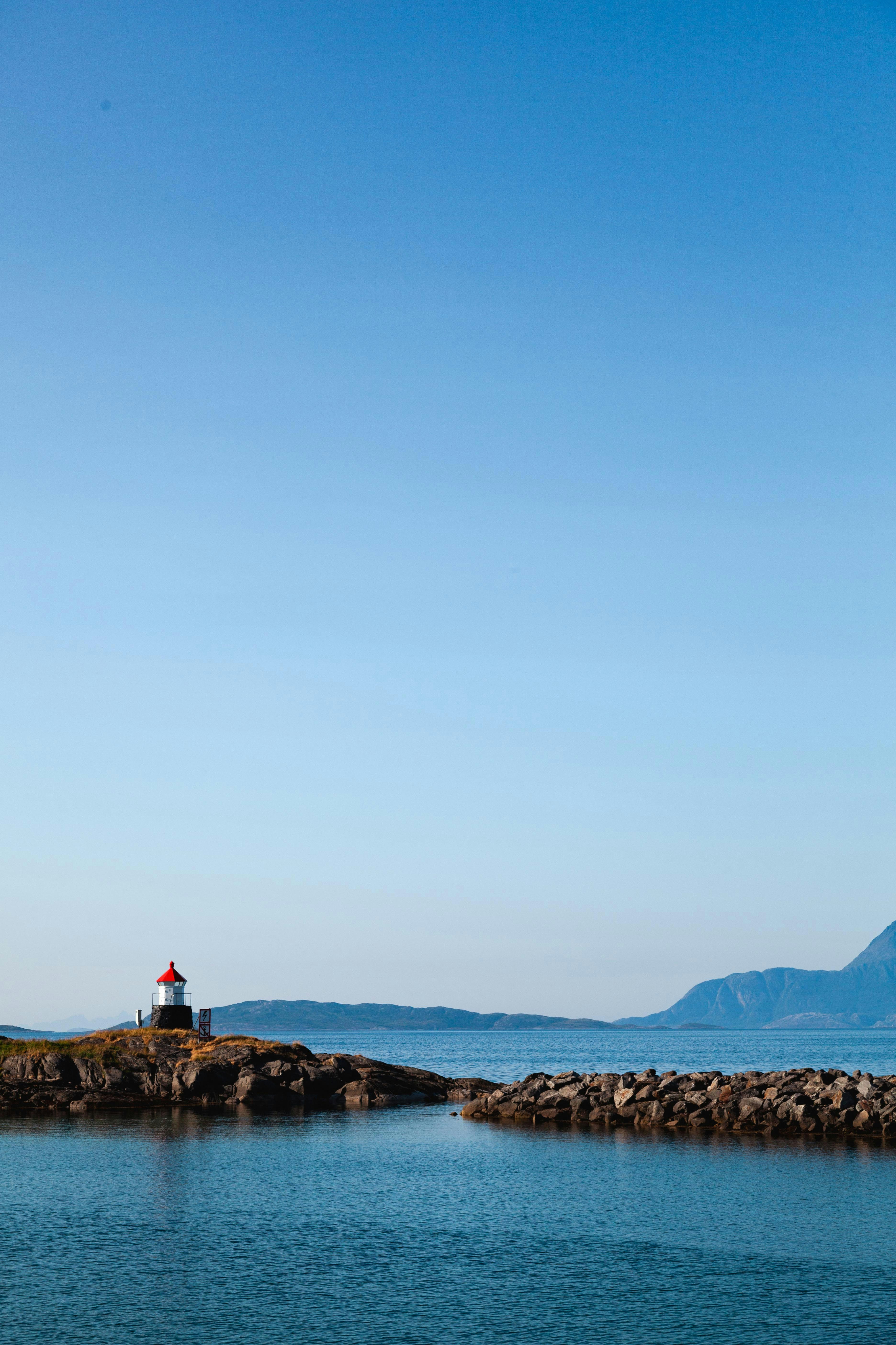 A lighthouse on a small island in the middle of the ocean photo – Free ...