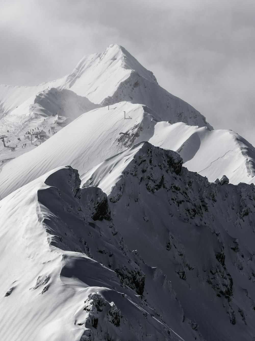 a very tall mountain covered in snow under a cloudy sky