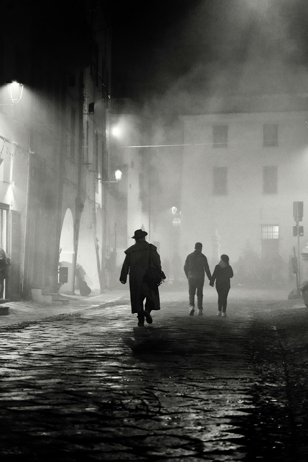 a group of people walking down a street at night