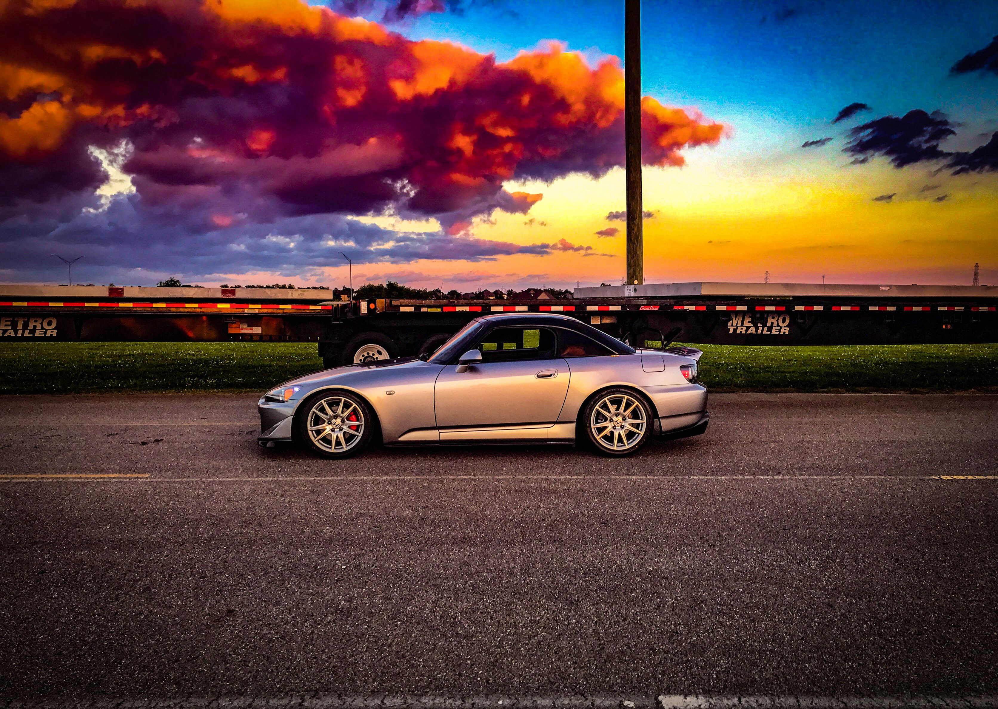 Sports car on open road with dramatic sunset and colorful sky