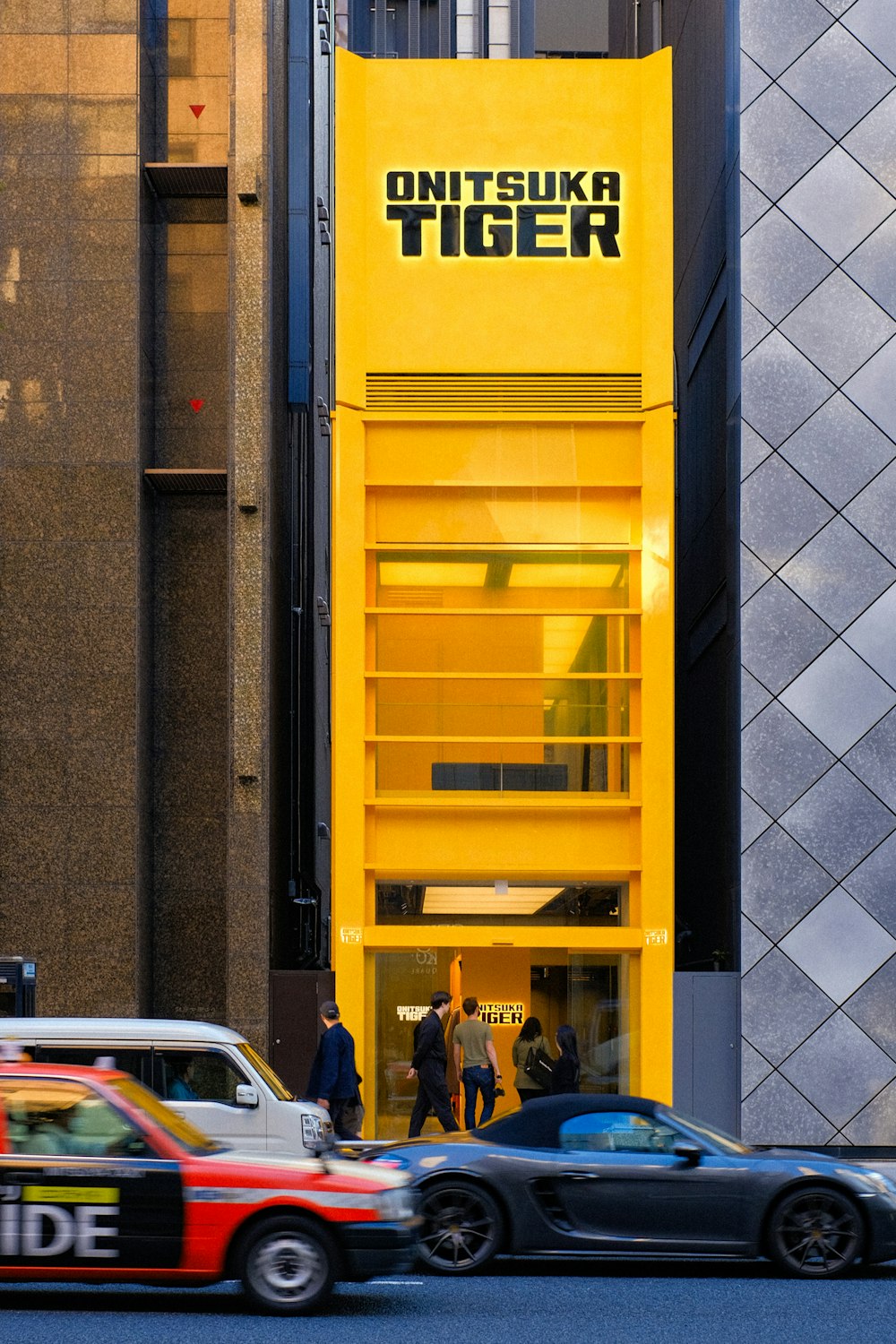 a taxi cab driving past a tall yellow building