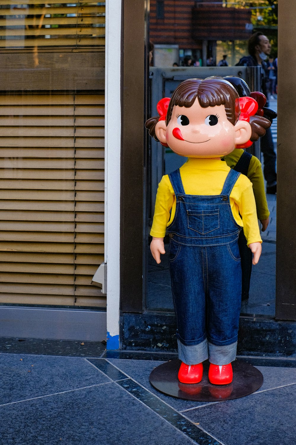 a statue of a girl wearing overalls and red shoes