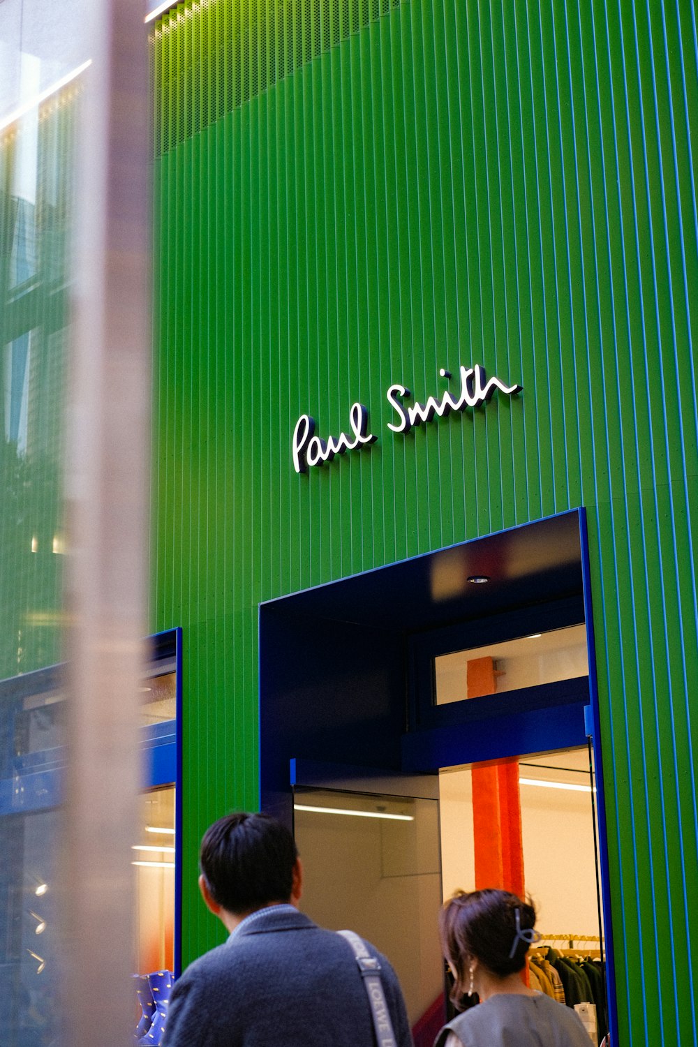 a couple of people standing outside of a green building