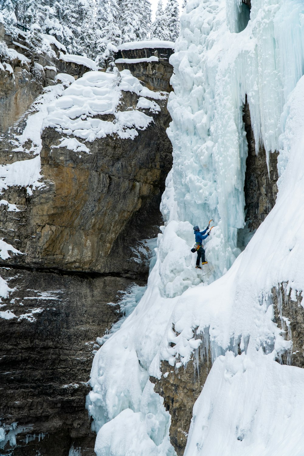 凍った滝のそばの崖の上に立つ男