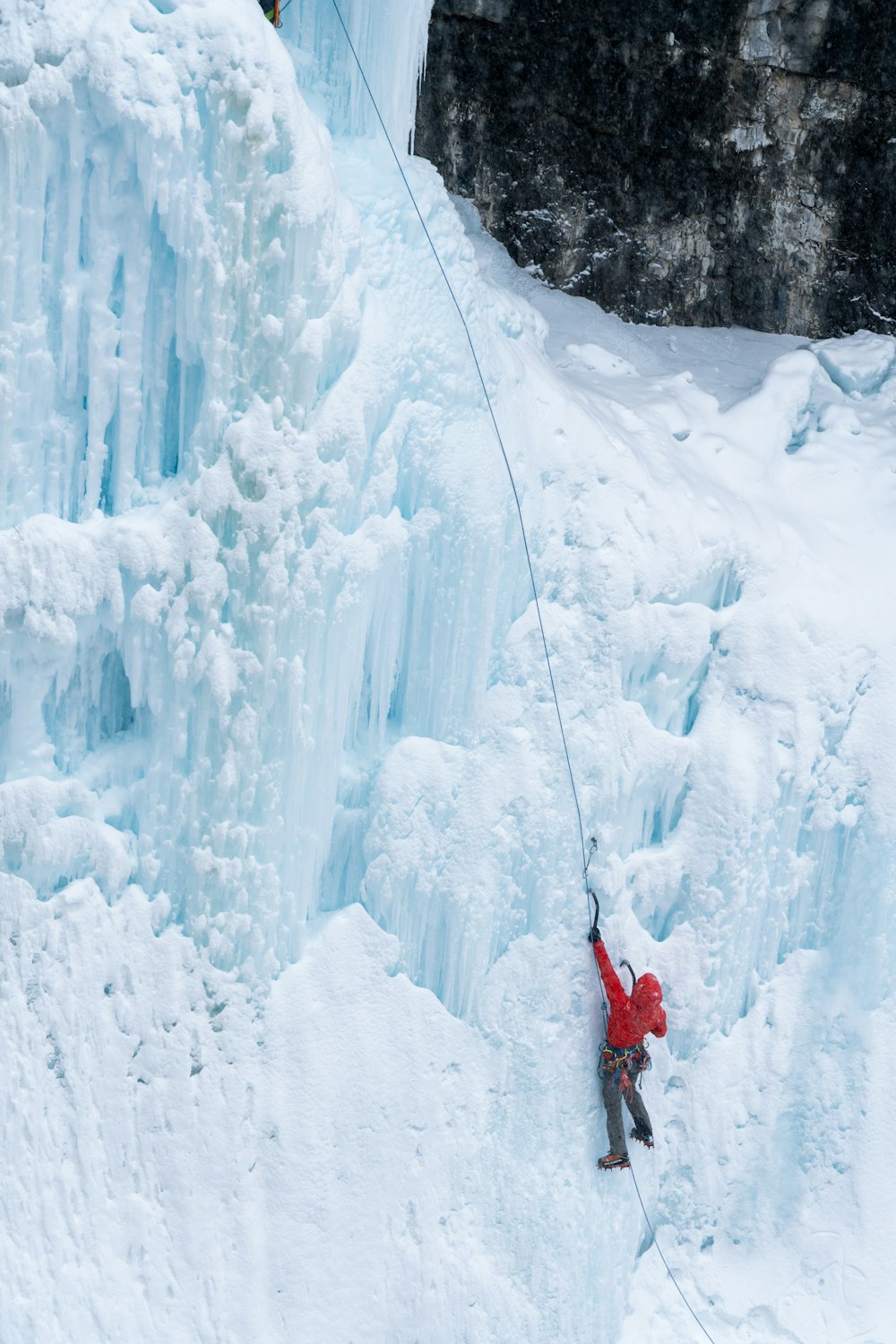 un uomo che si arrampica sul fianco di una cascata ghiacciata
