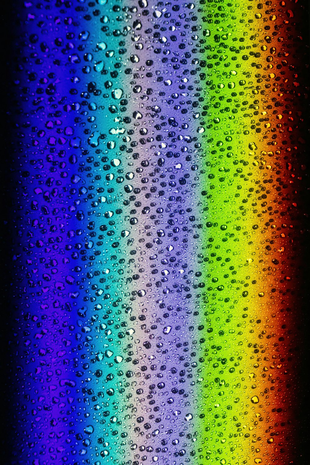 a rainbow of water droplets on a black background