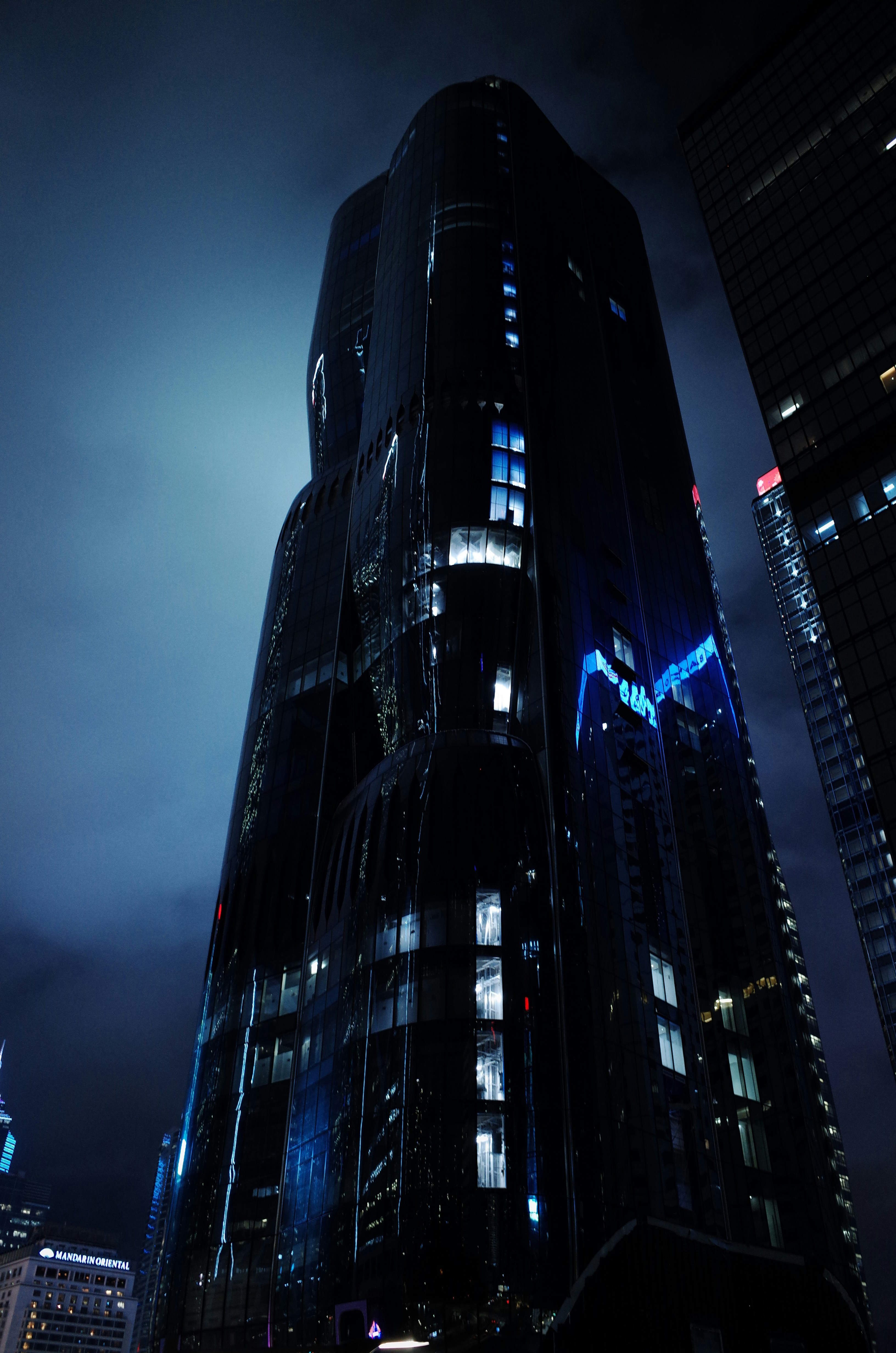 Luxury dark office with glowing neon blue cityscape view, wealthy atmosphere, dramatic cinematic shadows