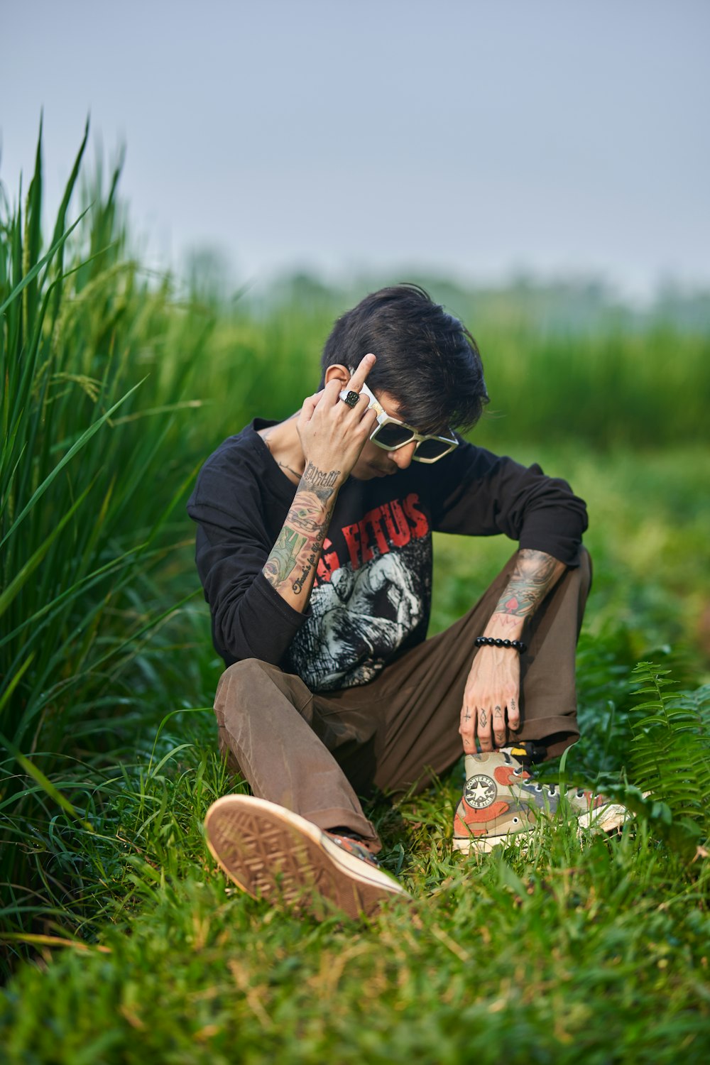 a man sitting in the grass talking on a cell phone