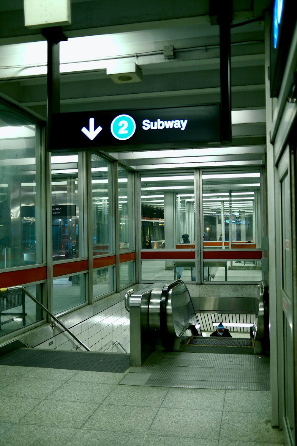 a subway entrance with an escalator and a bench