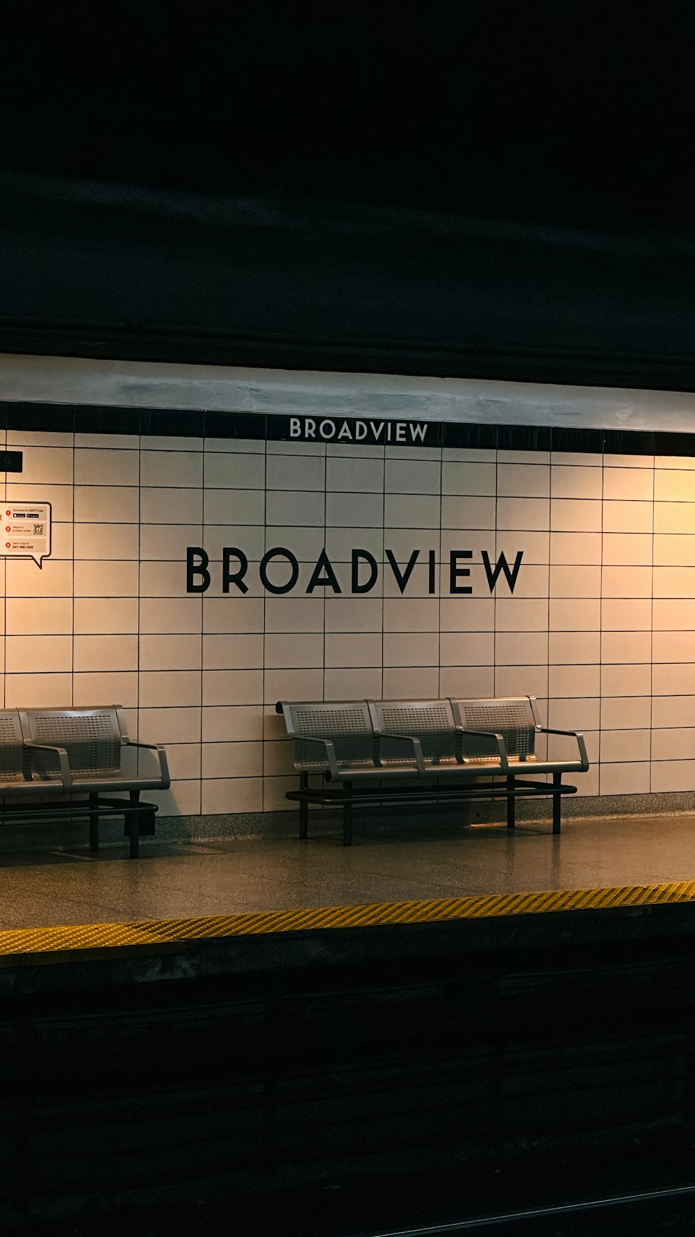 a subway station with benches and a sign on the wall