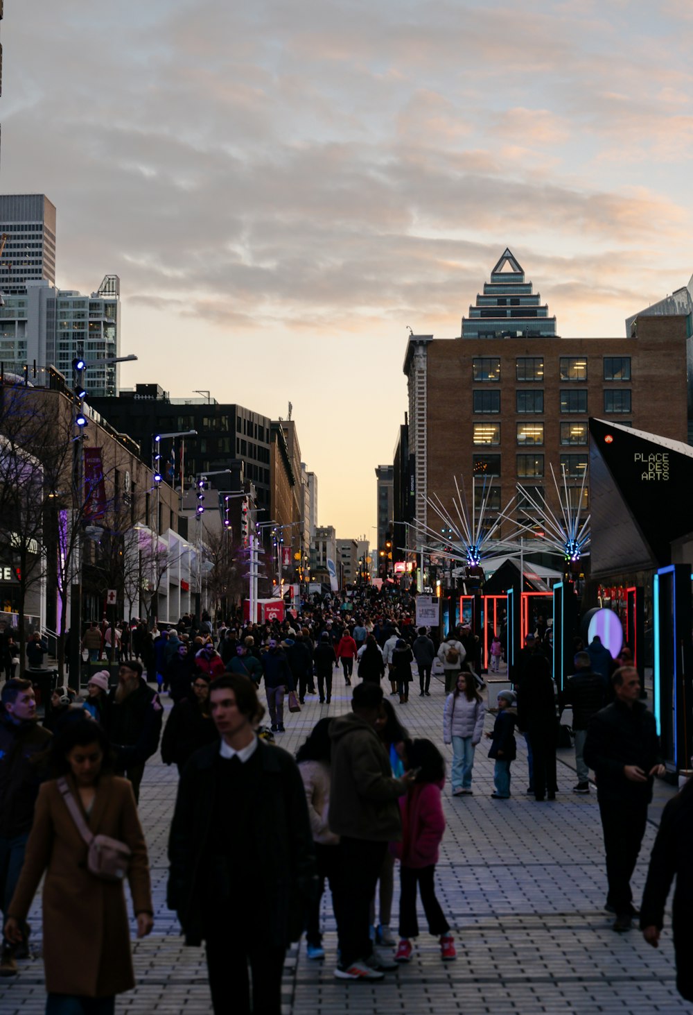 a crowd of people walking down a street next to tall buildings