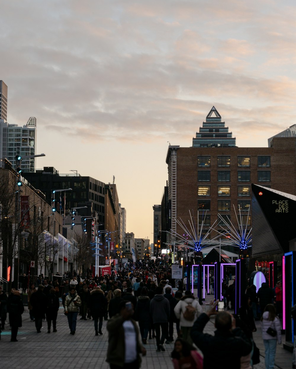 a crowd of people walking down a street next to tall buildings