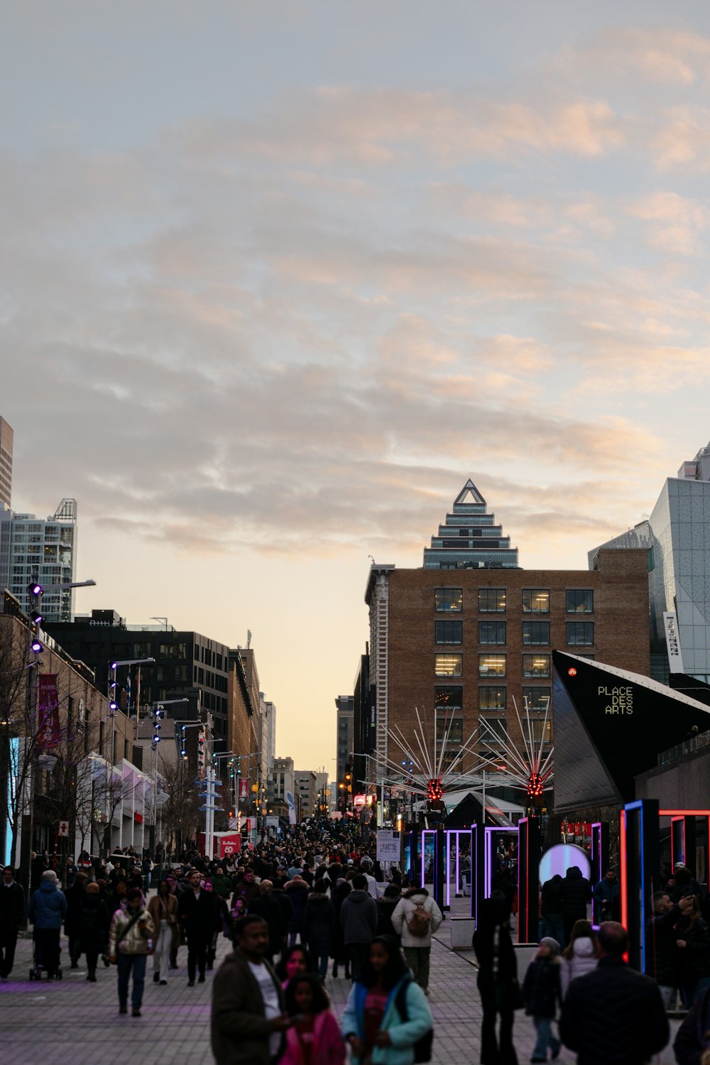 a crowd of people walking down a street next to tall buildings