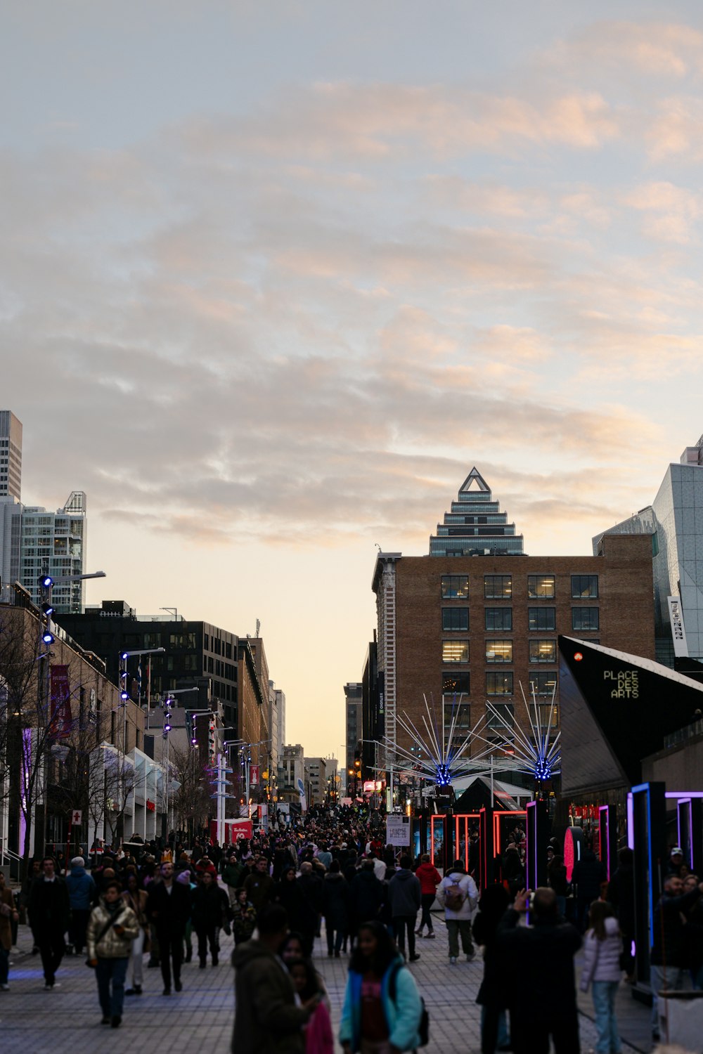 a crowd of people walking down a street next to tall buildings