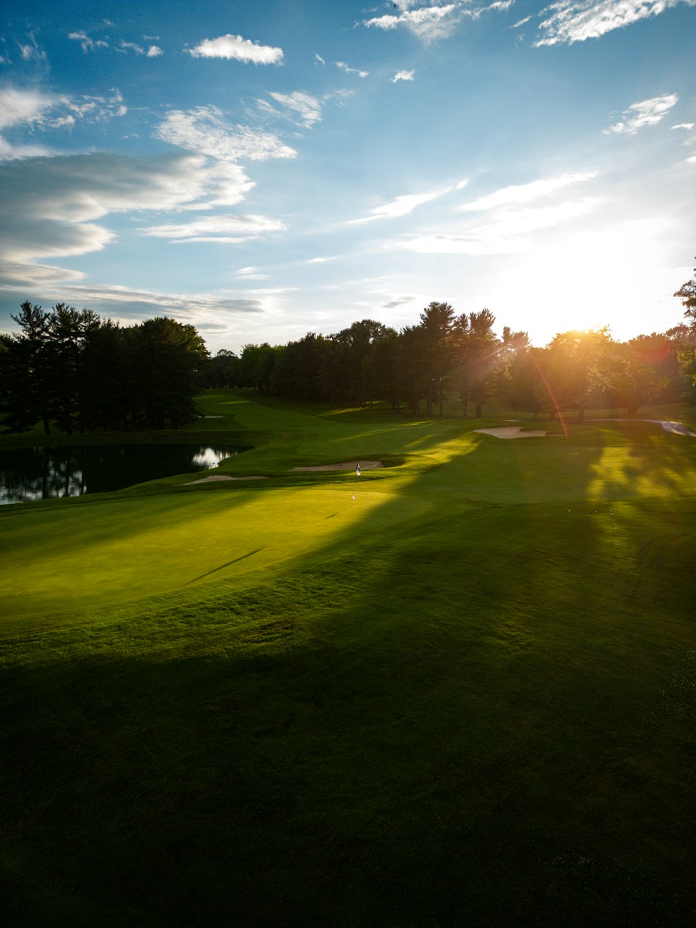 the sun is shining on a golf course