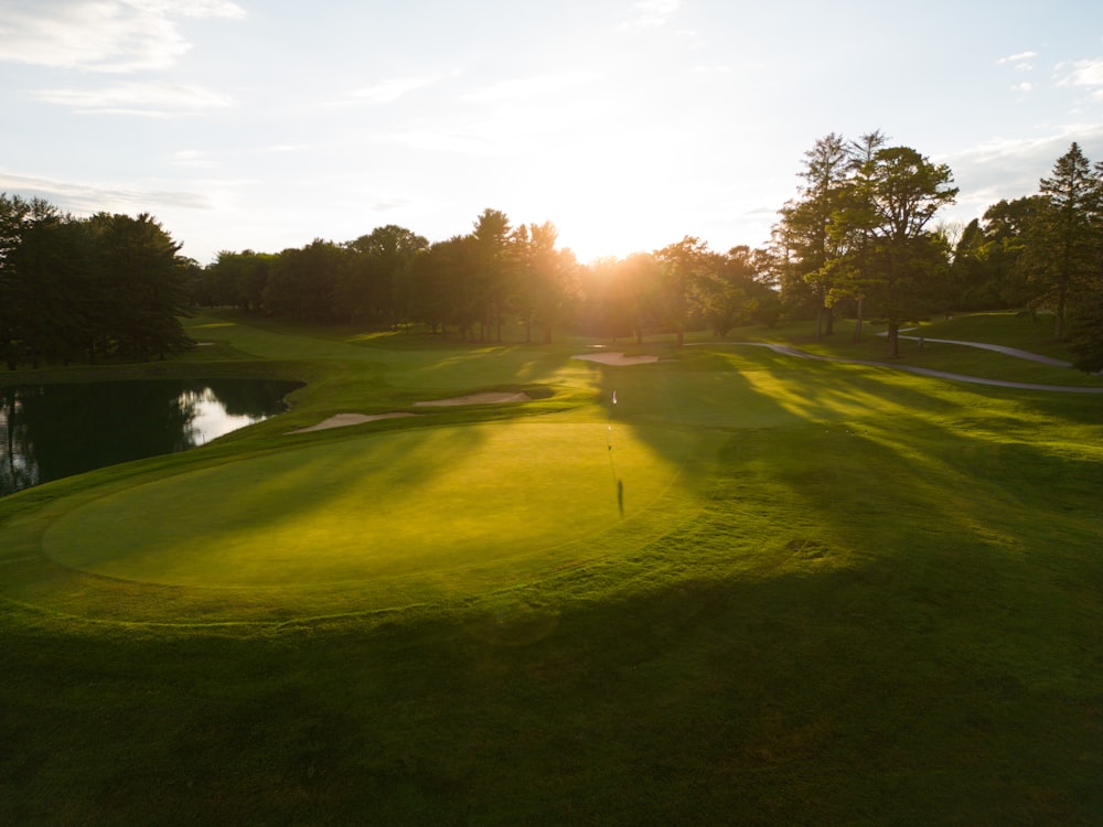 the sun is shining on the green of a golf course