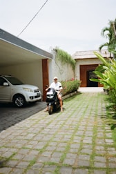 a man riding a scooter next to a white car