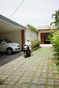 a man riding a scooter next to a white car