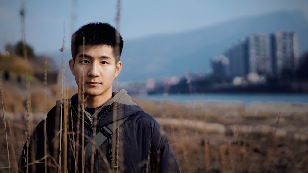 a young man standing in a field of tall grass