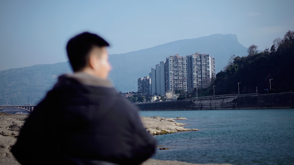 a man sitting on a rock looking at the water