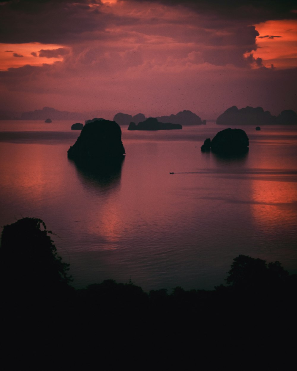 a sunset over a body of water with rocks in the water