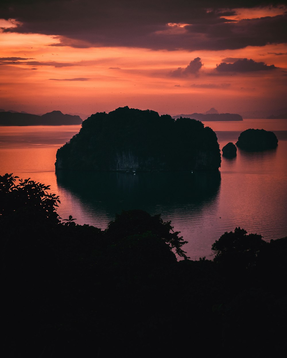 a sunset view of a small island in the middle of the ocean