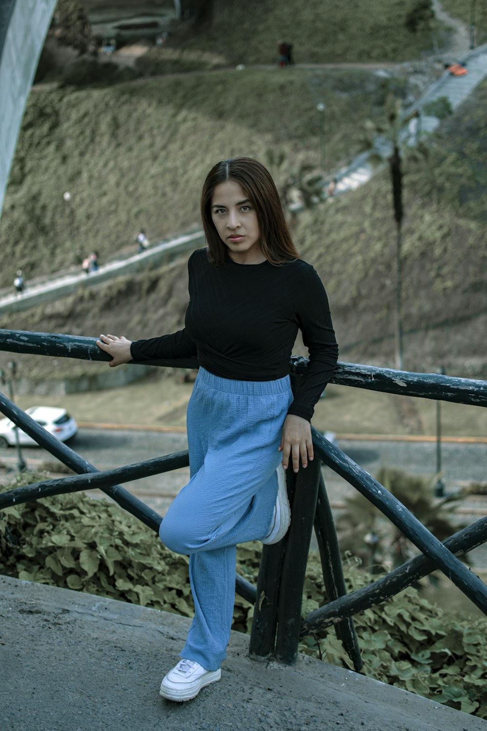 a woman leaning on a rail with her hands on her hips