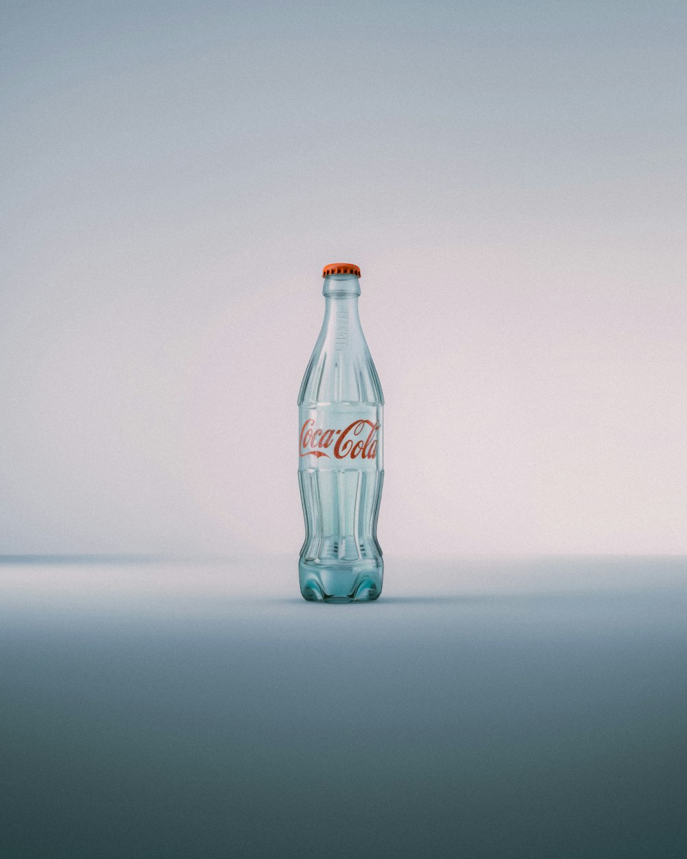 Una bottiglia di Coca Cola seduta sopra un tavolo
