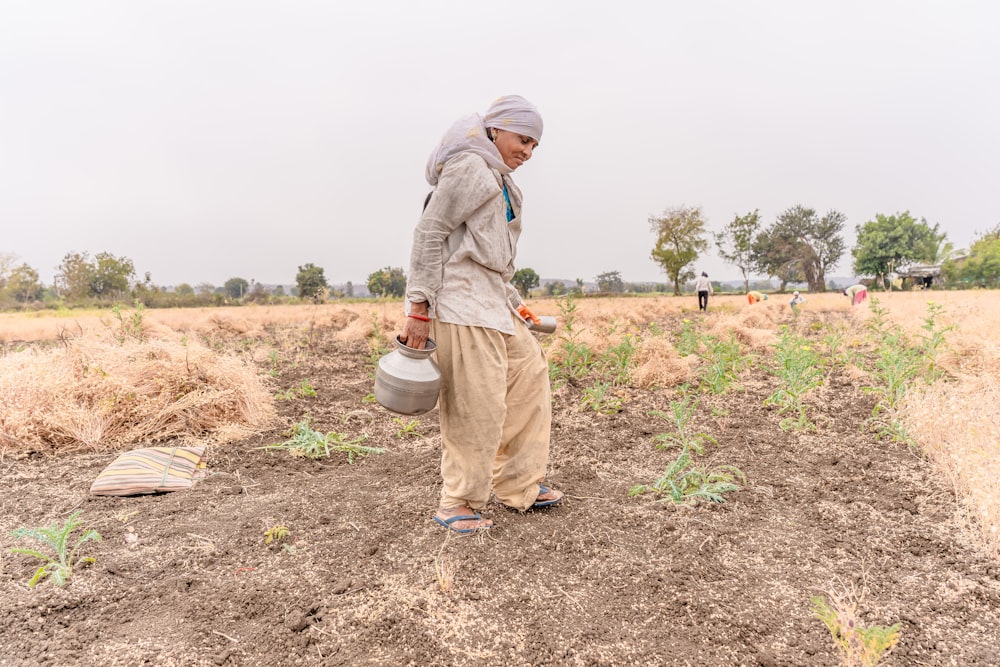 a man standing in a field holding a bucket