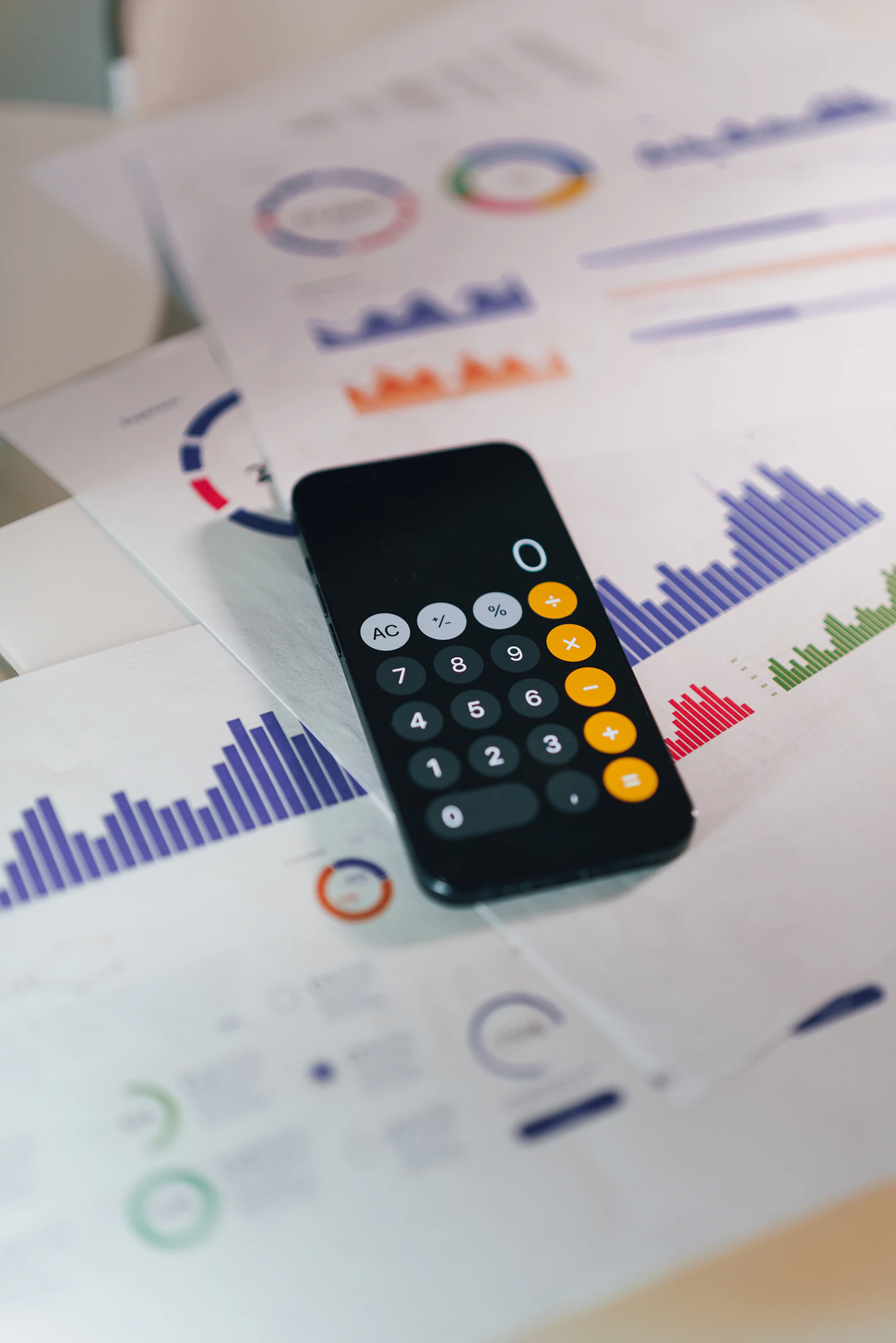 Phone calculator lying on printed financial reports