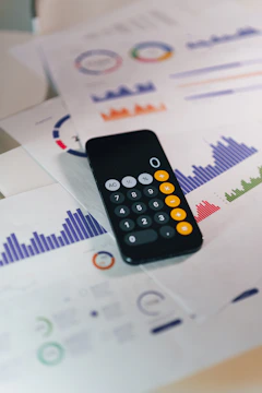 A phone calculator resting on printed financial reports