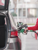 a woman pumping gas into her car at a gas station
