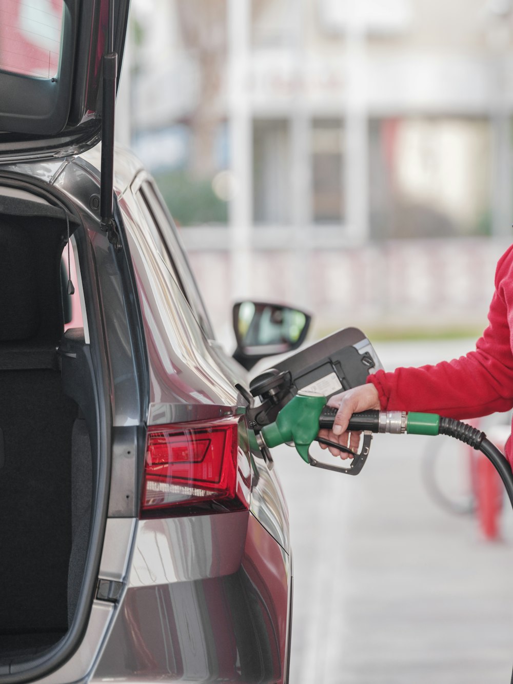 a woman pumping gas into her car at a gas station