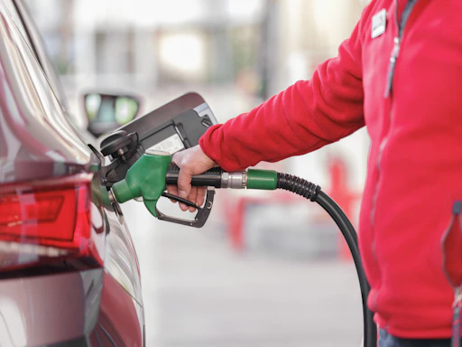 a person filling a car with gas at a gas station