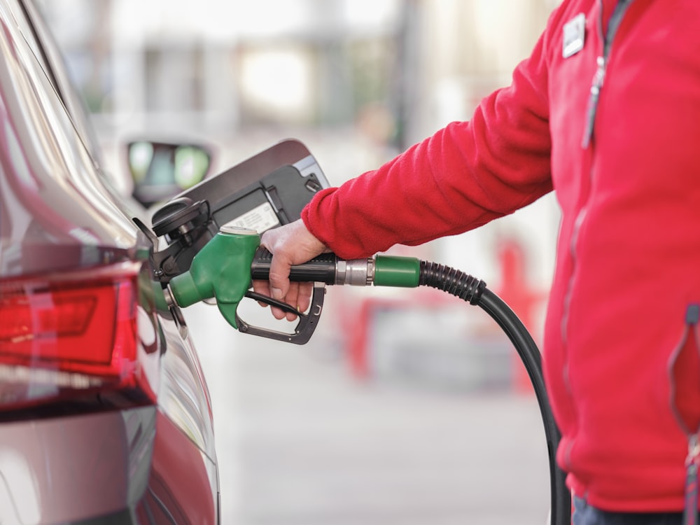 a person filling a car with gas at a gas station