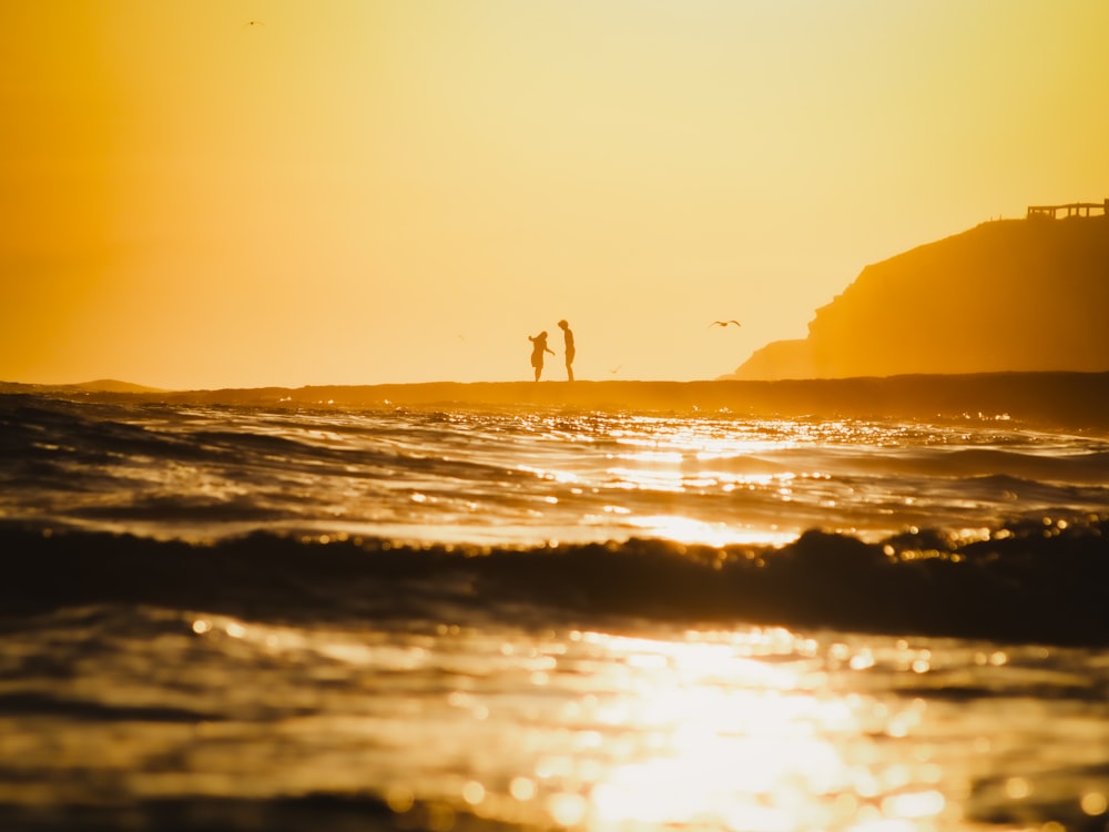 a couple of people standing on top of a surfboard in the ocean