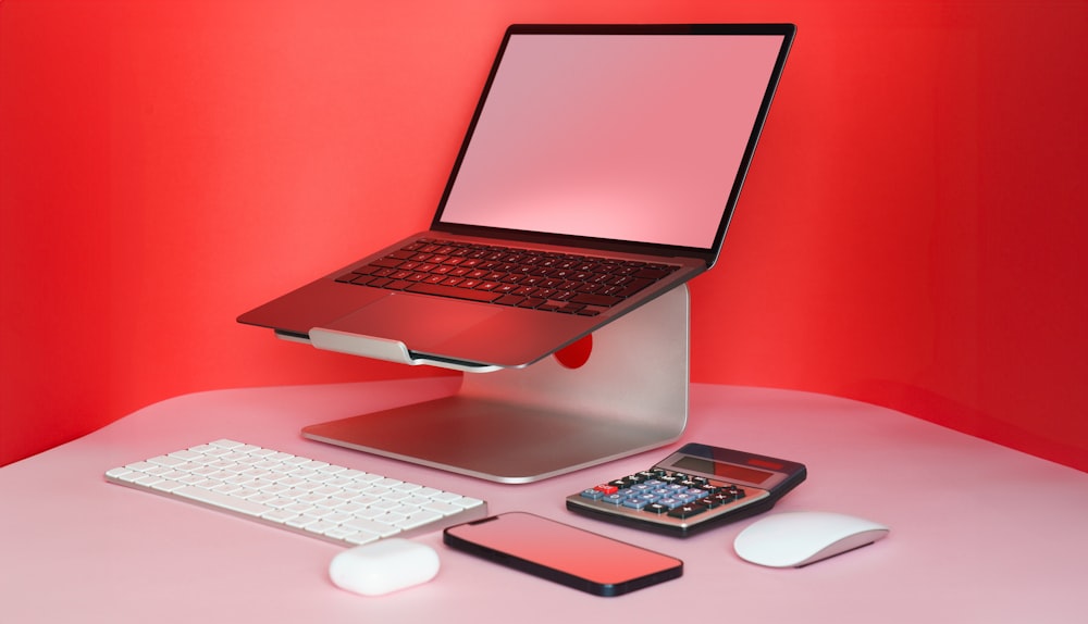 un computer portatile seduto sopra una scrivania accanto a una tastiera