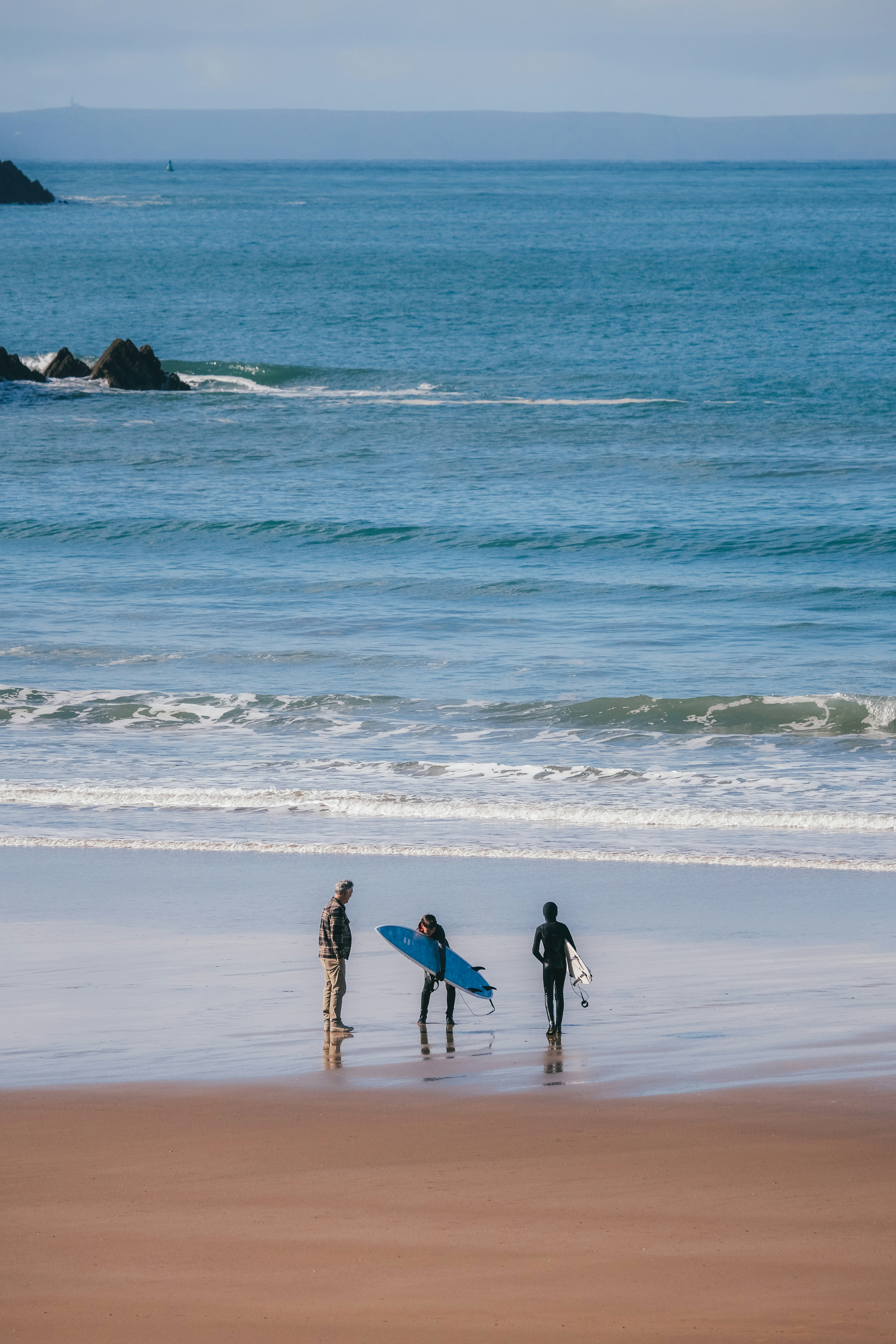 a group of people standing on top of a beach next to the ocean