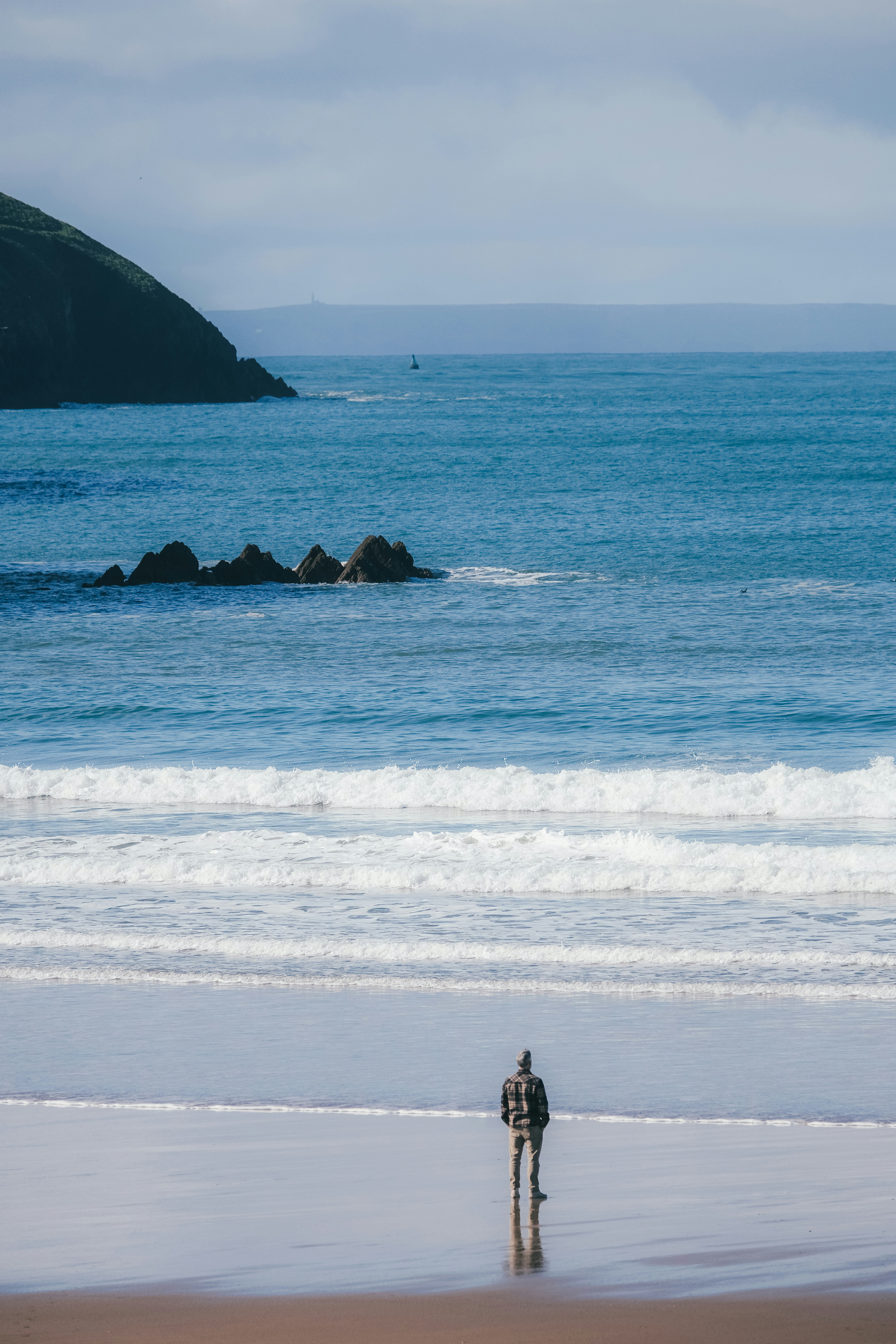 a couple of people standing on top of a beach next to the ocean