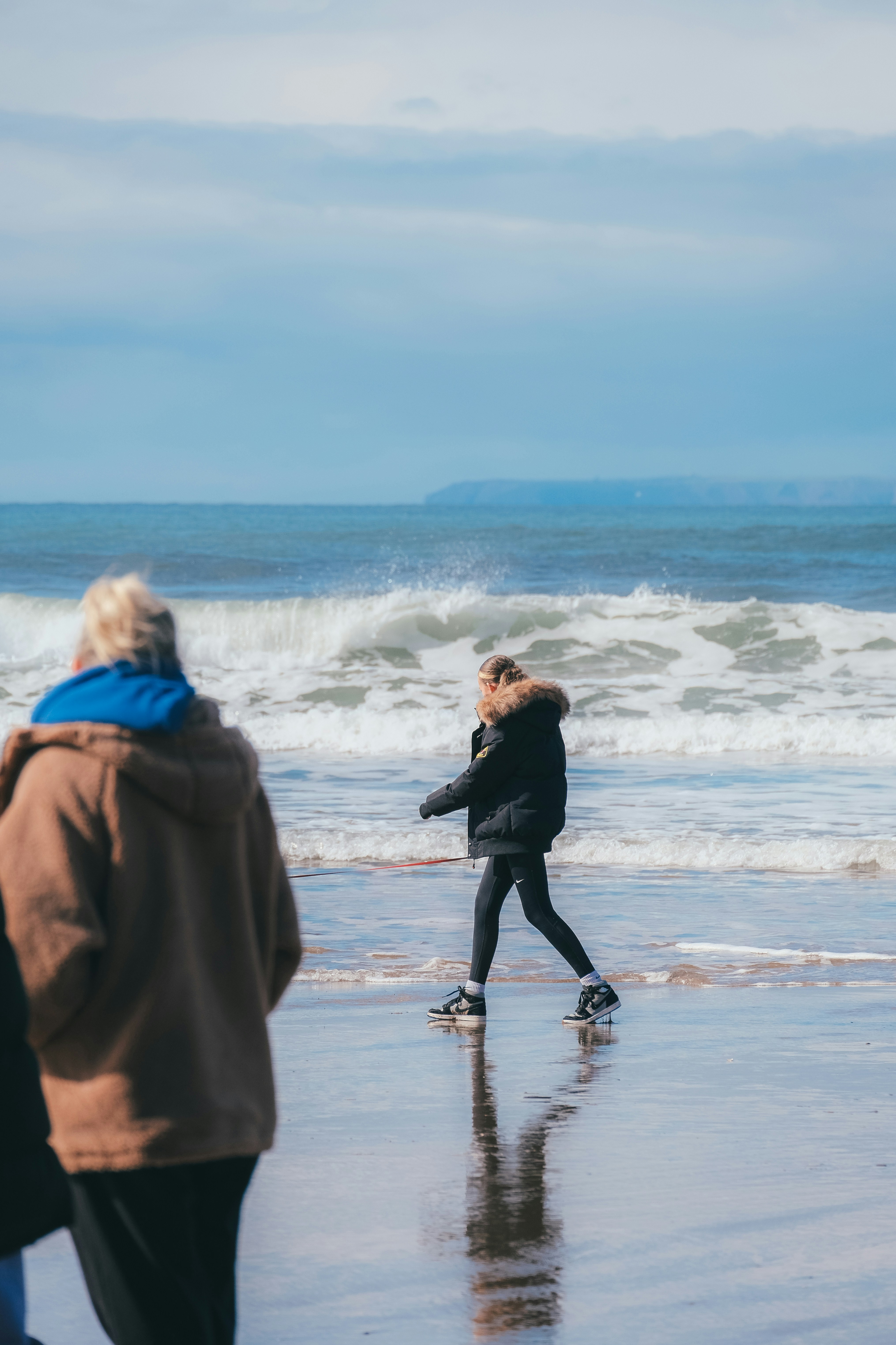 a woman walking along a beach next to the ocean