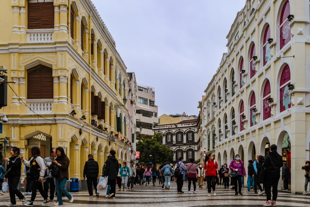 a group of people walking down a street next to tall buildings