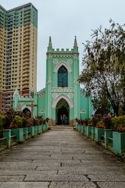 a large green church with a tall building in the background