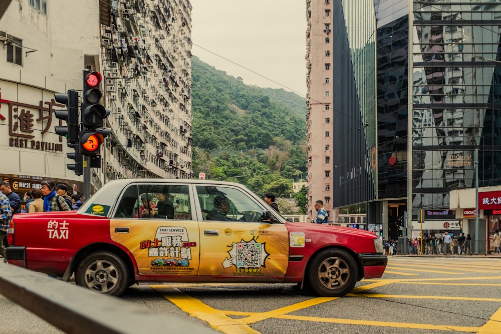 a red taxi cab driving down a street next to tall buildings