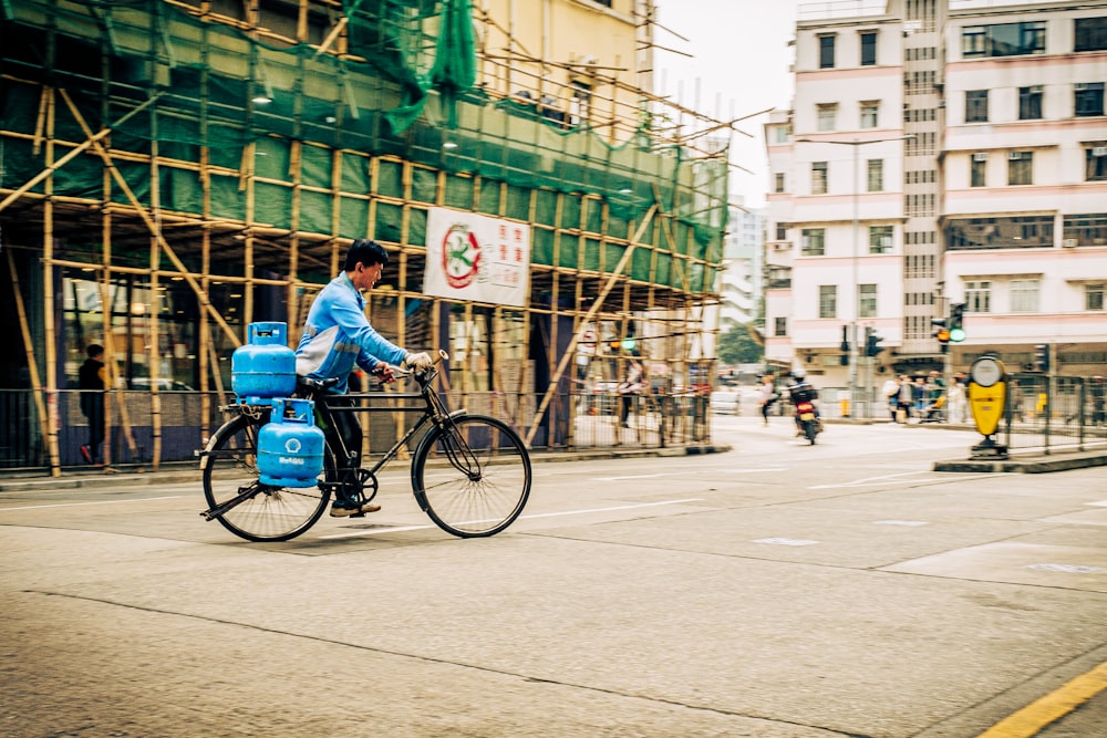 a man riding a bike down a street next to tall buildings